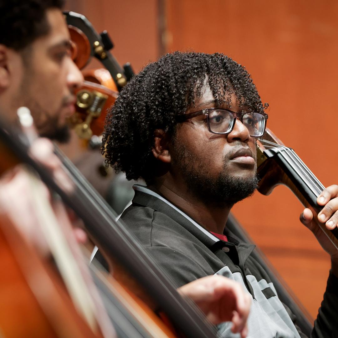Two CCM graduate students play double bass during a CCM Philharmonia rehearsal.