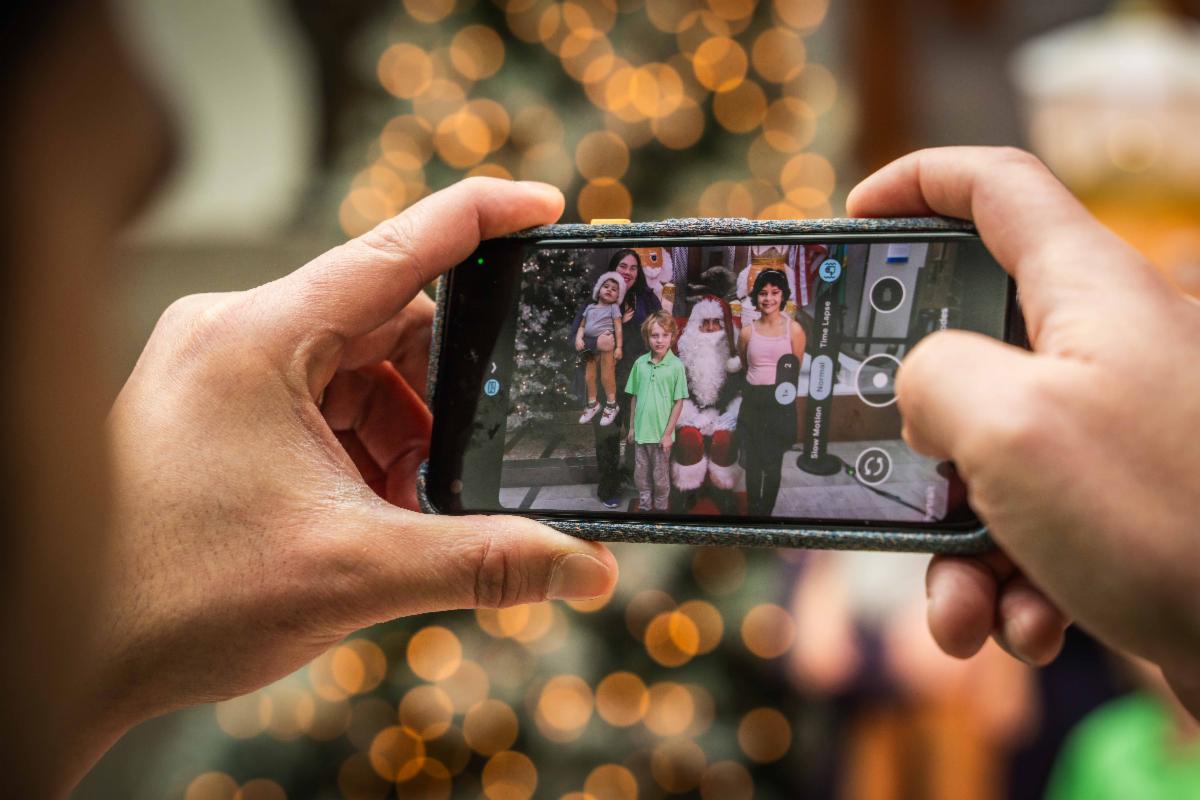 A closeup photo of someone's phone as they take a photo of their family with Santa