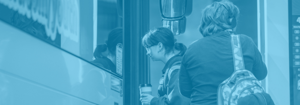 A blue duotone photo of youth boarding an STA bus.