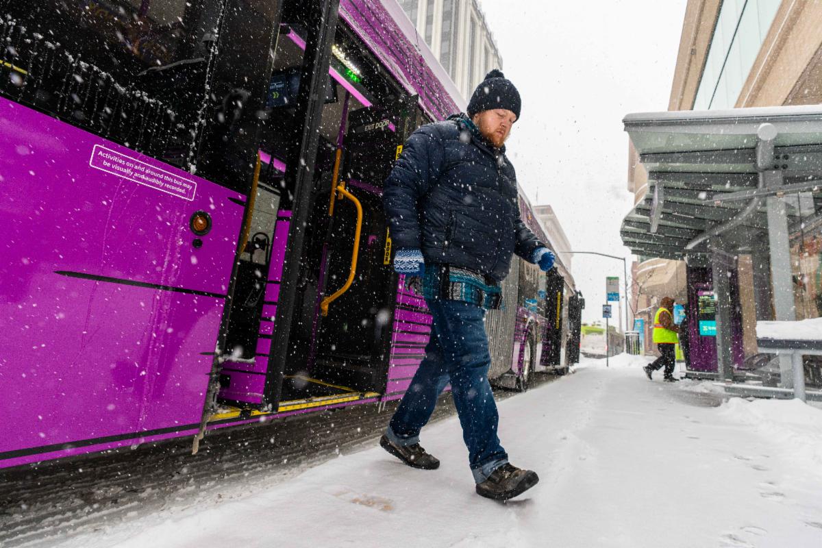 A photo of a rider alighting a City Line bus in the snow at STA Plaza
