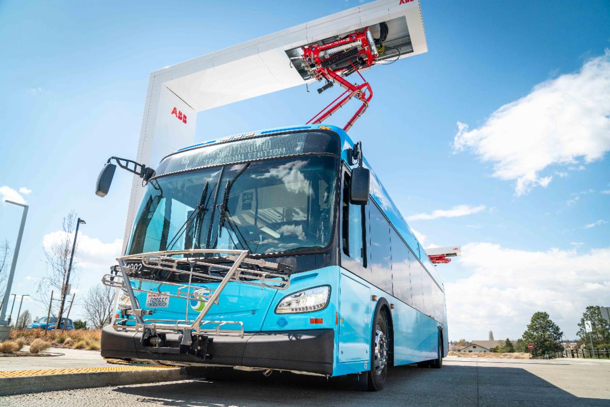 A photo of an STA battery-electric bus being charged at an overhead pantograph charger