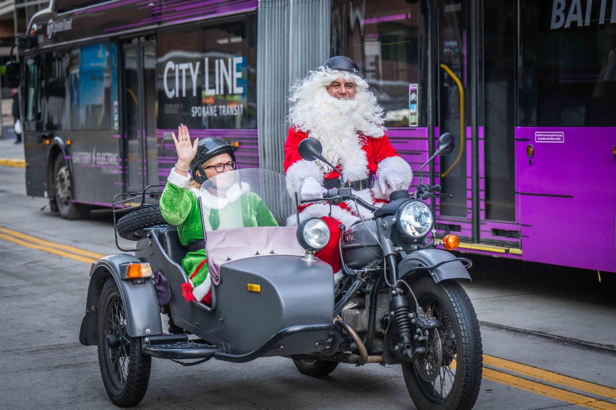 A photo of Santa and an elf riding in a motorcycle and sidecar