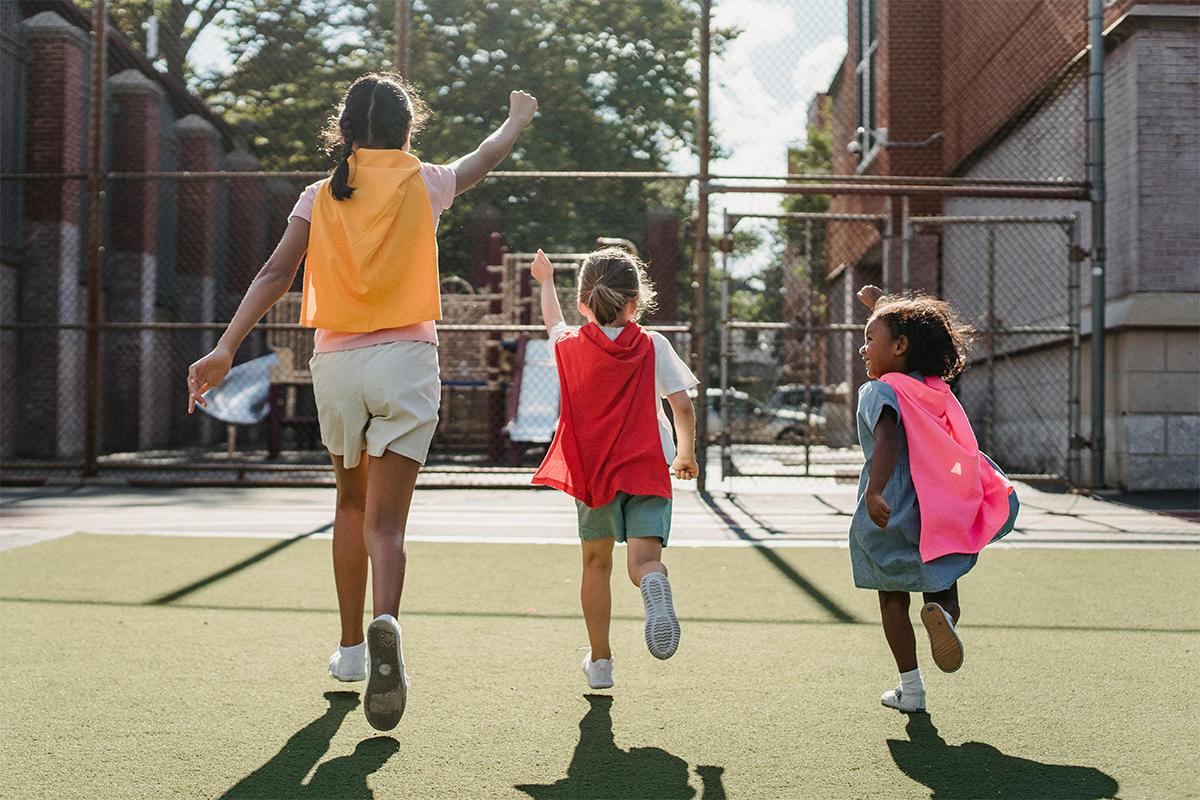 Different aged kids running with capes.