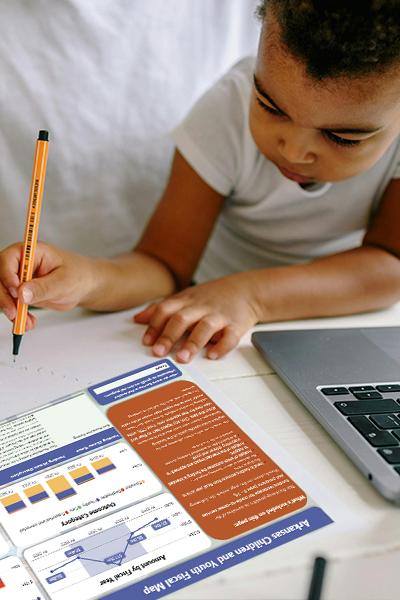 Young child drawing next to laptop.