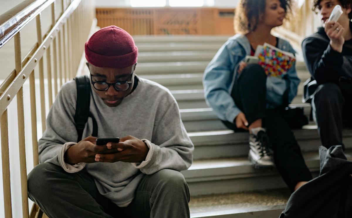 Kid on phone isolated from their friends.