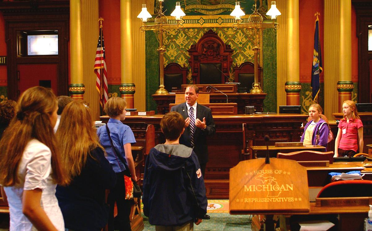 State legislator talking to youth in congressional chamber.