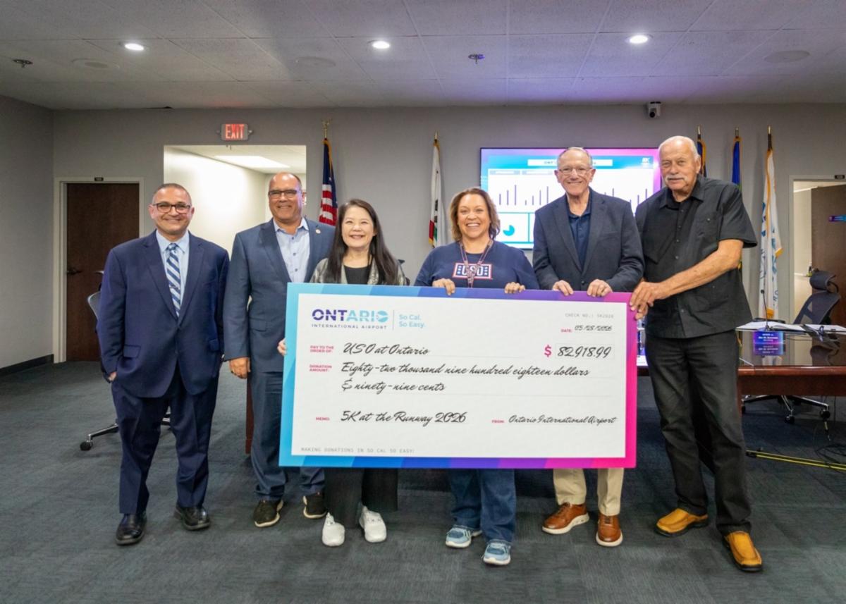 A group of people stand smiling and holding a giant check for nearly $83,000 to ONT's 5K 