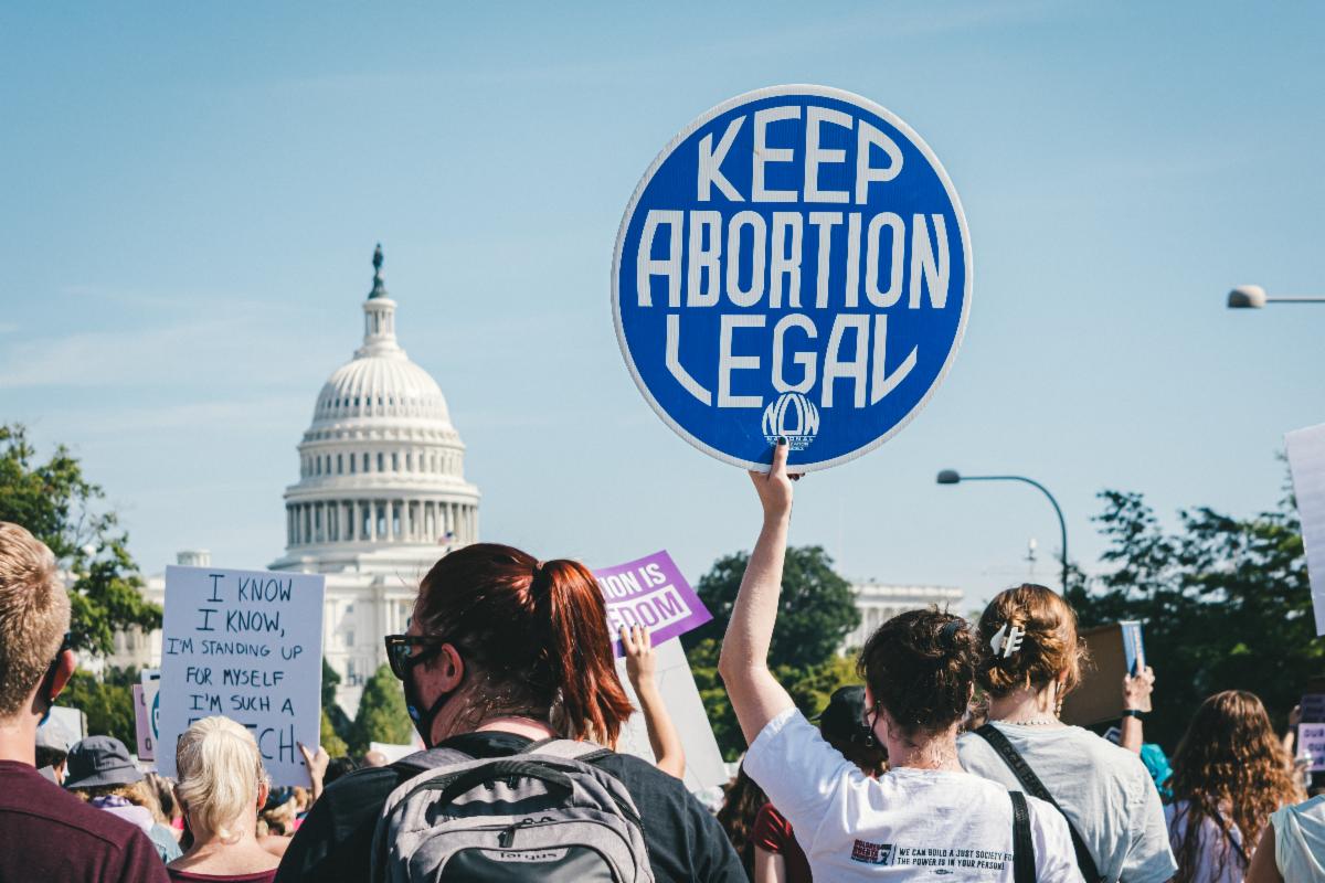 A person in front of the Capitol holding a sign that says Keep Abortion Legal