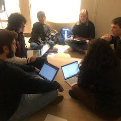 Students sit in a circle working on their writing.