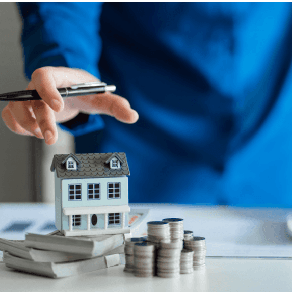 Person touching small house on top of money.