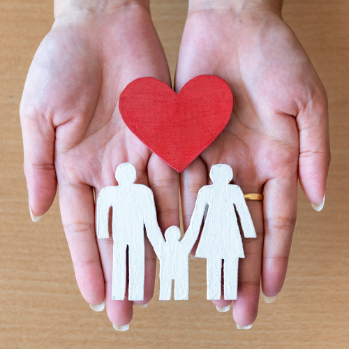 Photo of two hands holding a cut-out paper heart and a cut-out family