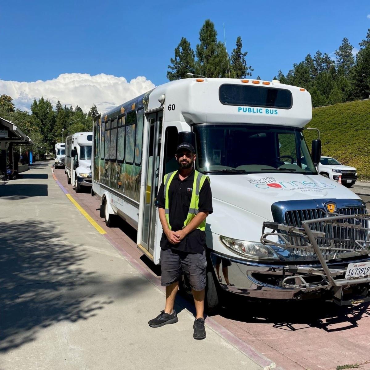 Person in bright yellow vest standing in front of Nevada County Connects bus