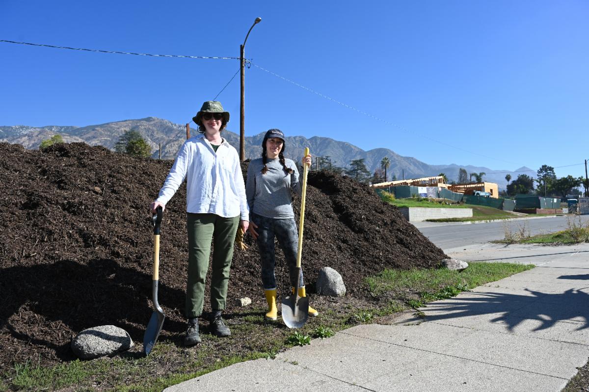 Lydia Whitlock (left) and Natalie Levy (right) stand next to a pile of composted mulch used to cap the soil on multiple Altadena properties