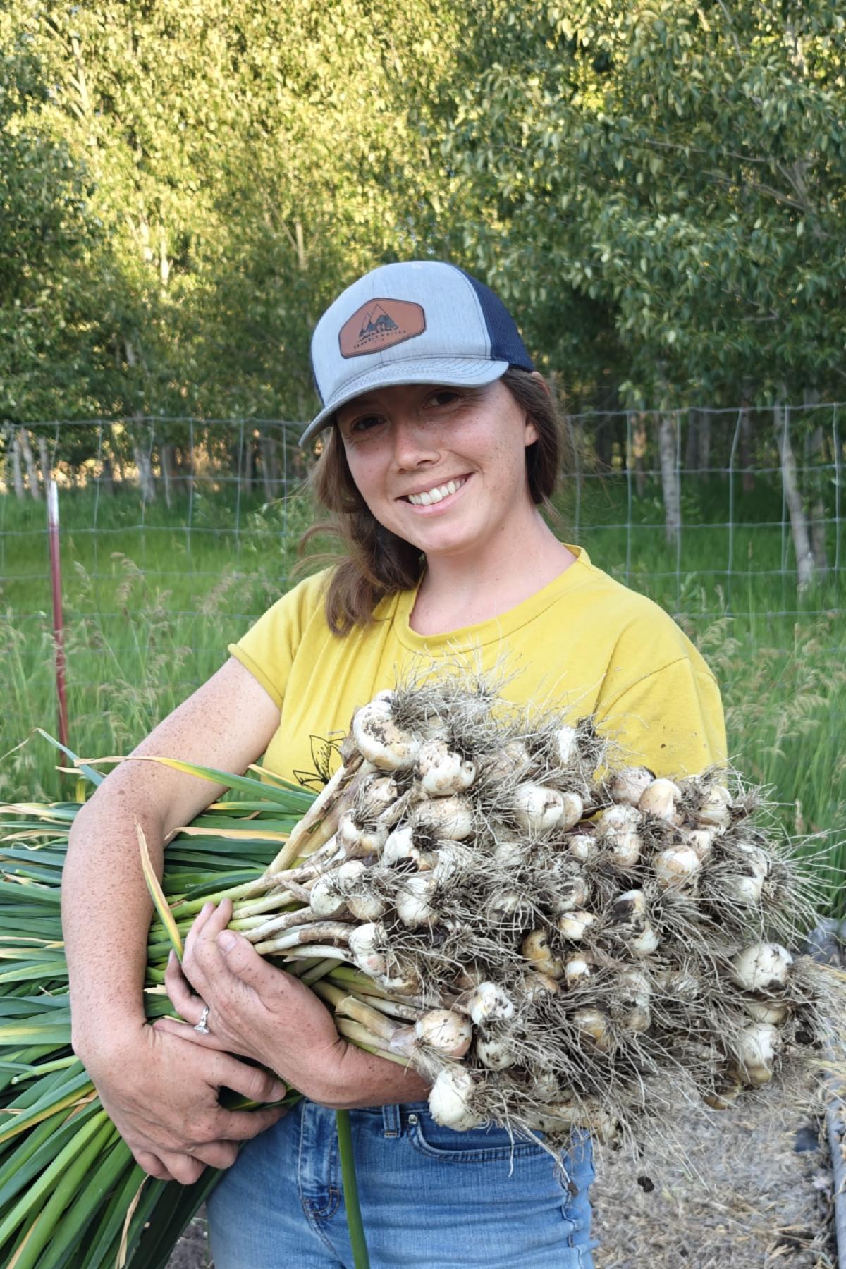 Ary West holds a freshly harvested armful of garlic at Trouble Valley Farm