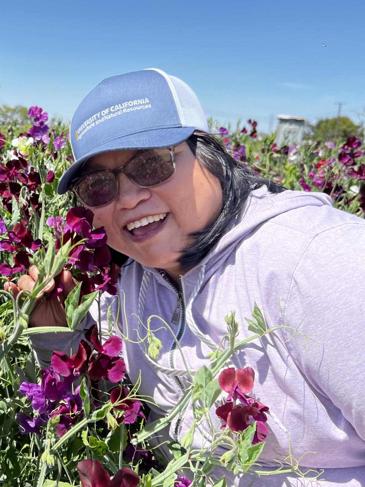Community educator Fam Lee leans toward some flowers in a field