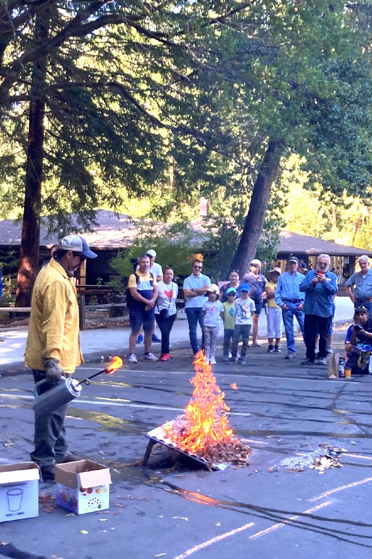 A fire expert uses a torch to demonstrate fire behavior as the crowd at the Good Fire Fair looks on
