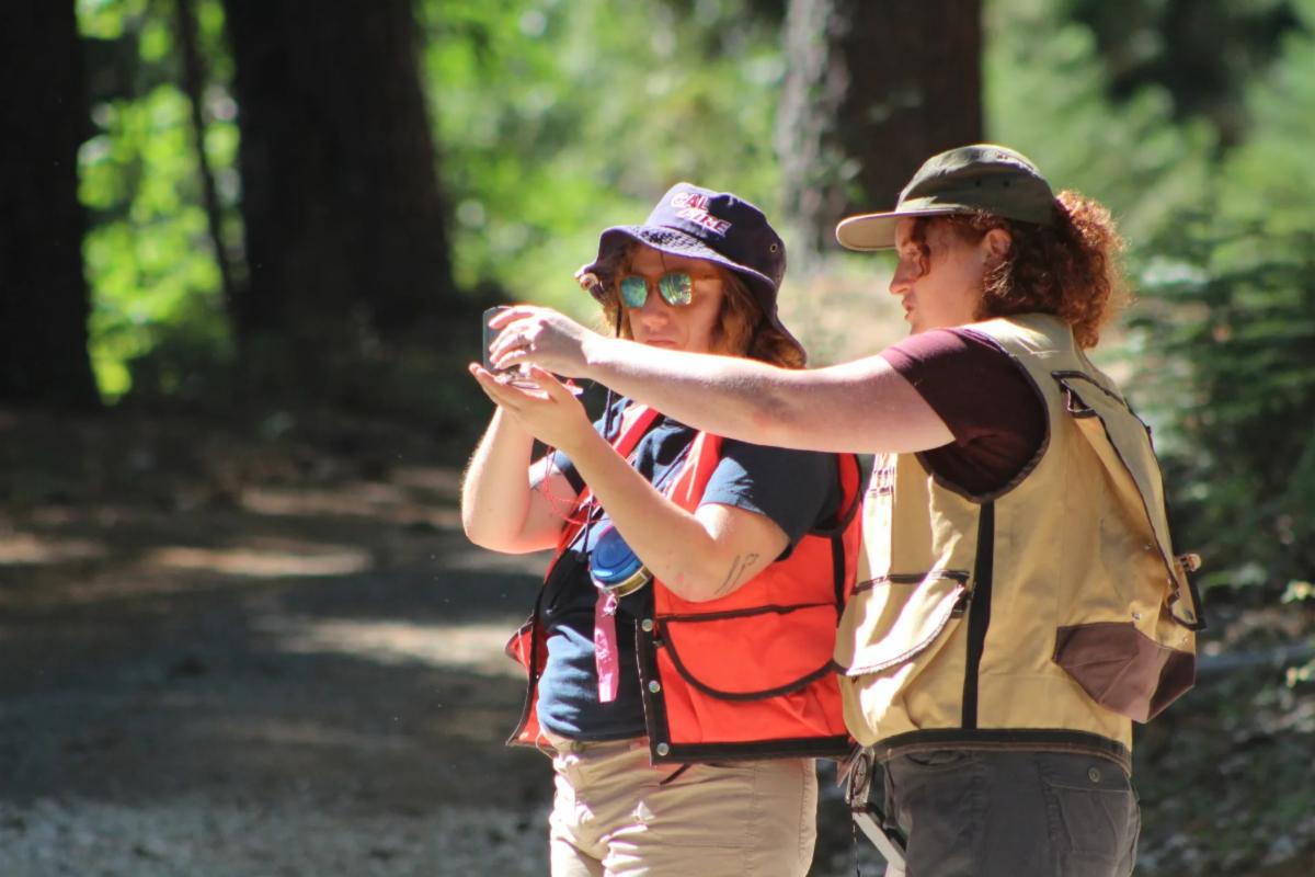 Katie Reidy (right) helps a student with forest orienteering skills during Forestry Mini Camp