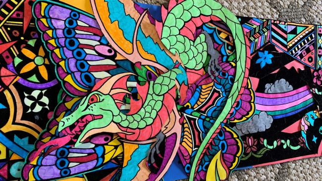 brightly colored designs on a felt background depicting dragons, butterflies, flowers, the man in the moon and a rainbow and clouds