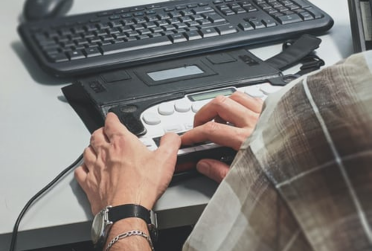 closeup of an accessible keyboard and computer with a hand on the keyboard