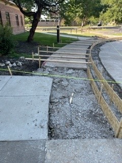 A section of sidewalk in front of the Independence, Incorporated building is torn out and wood concrete forms are in place, waiting for new concrete to be poured.