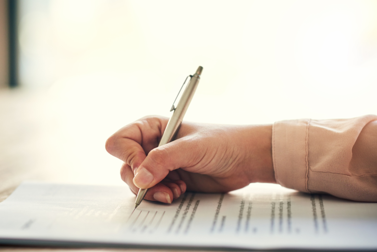 A person filling out a form with their right hand using a pen.