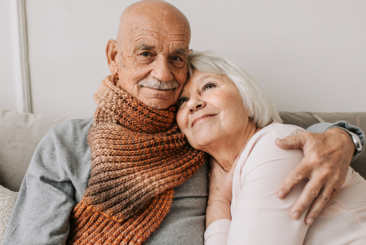 An older man and woman embracing each other.