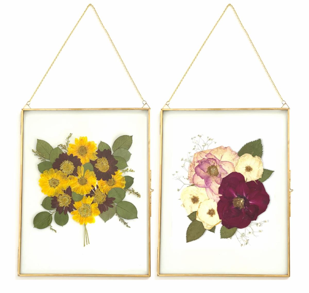 Two hanging glass frames with pressed flowers.