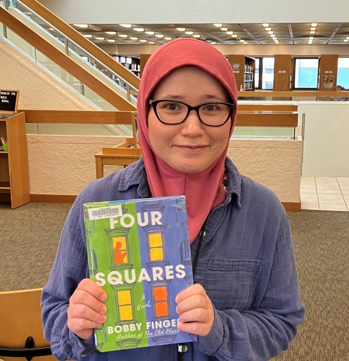 A woman holds a copy of the book "Four Squares"