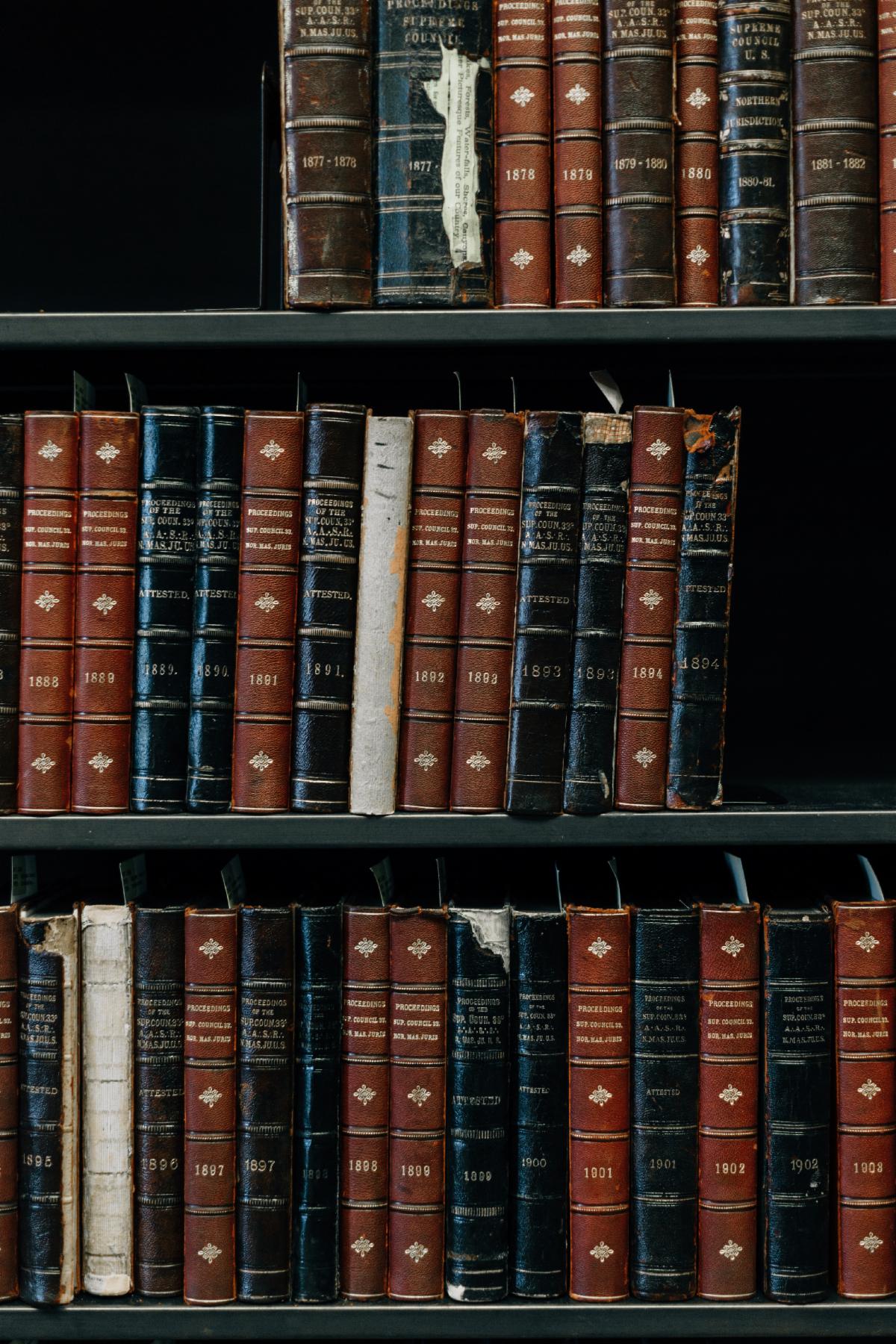 Tattered books on wooden library shelves. Photo by Erol Ahmed on Unsplash.