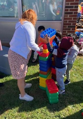 young students and teacher engaging in outdoor activity stacking blocks