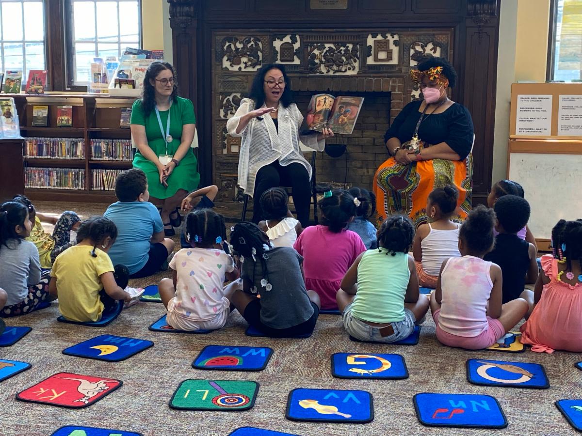 Commissioner Rosa reading a picture book to children assembled at the Albany Public Library's historic Howe Branch.