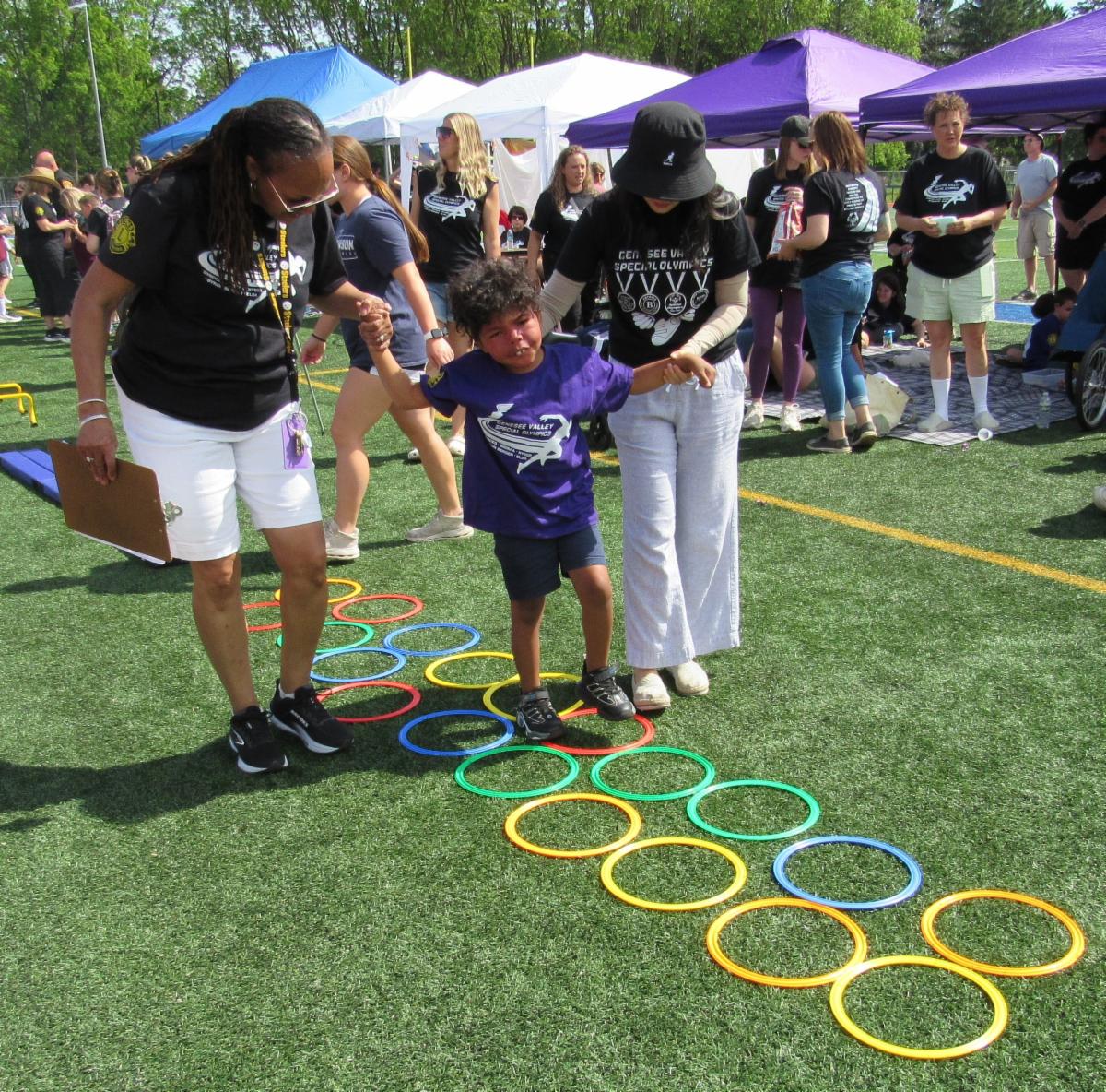 New York State School for the Blind Special Olympics, student being helped by two teachers