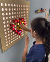 young girl with ponytail designing a red heart with tiles on the wall