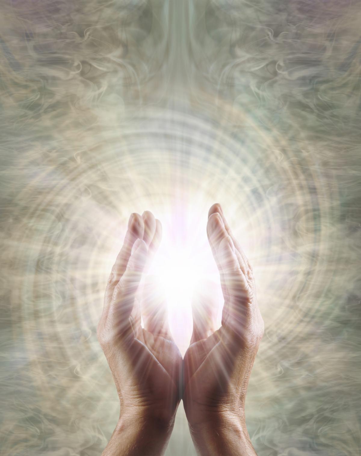male parallel hands with white star light between against a spinning vortex copy space background ideal for a spiritual holistic healing theme