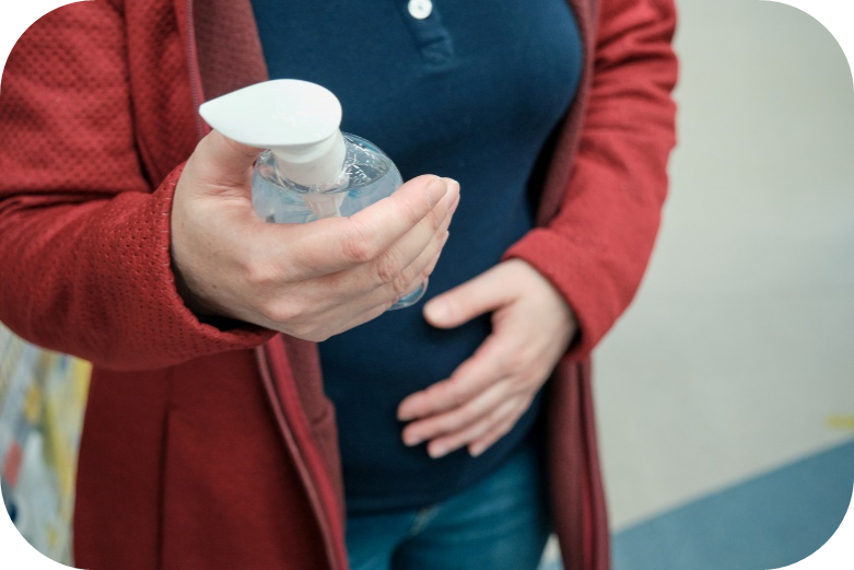 Pregnant person in store examines the label on a bottle of hand sanitizer.
Una persona embarazada en una tienda