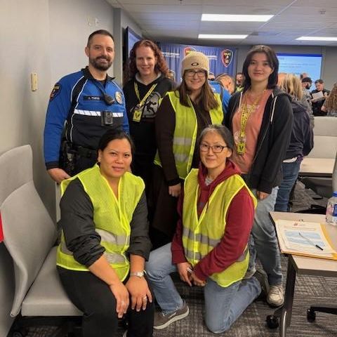 Group of women in yellow safety vests and police officer smiling 