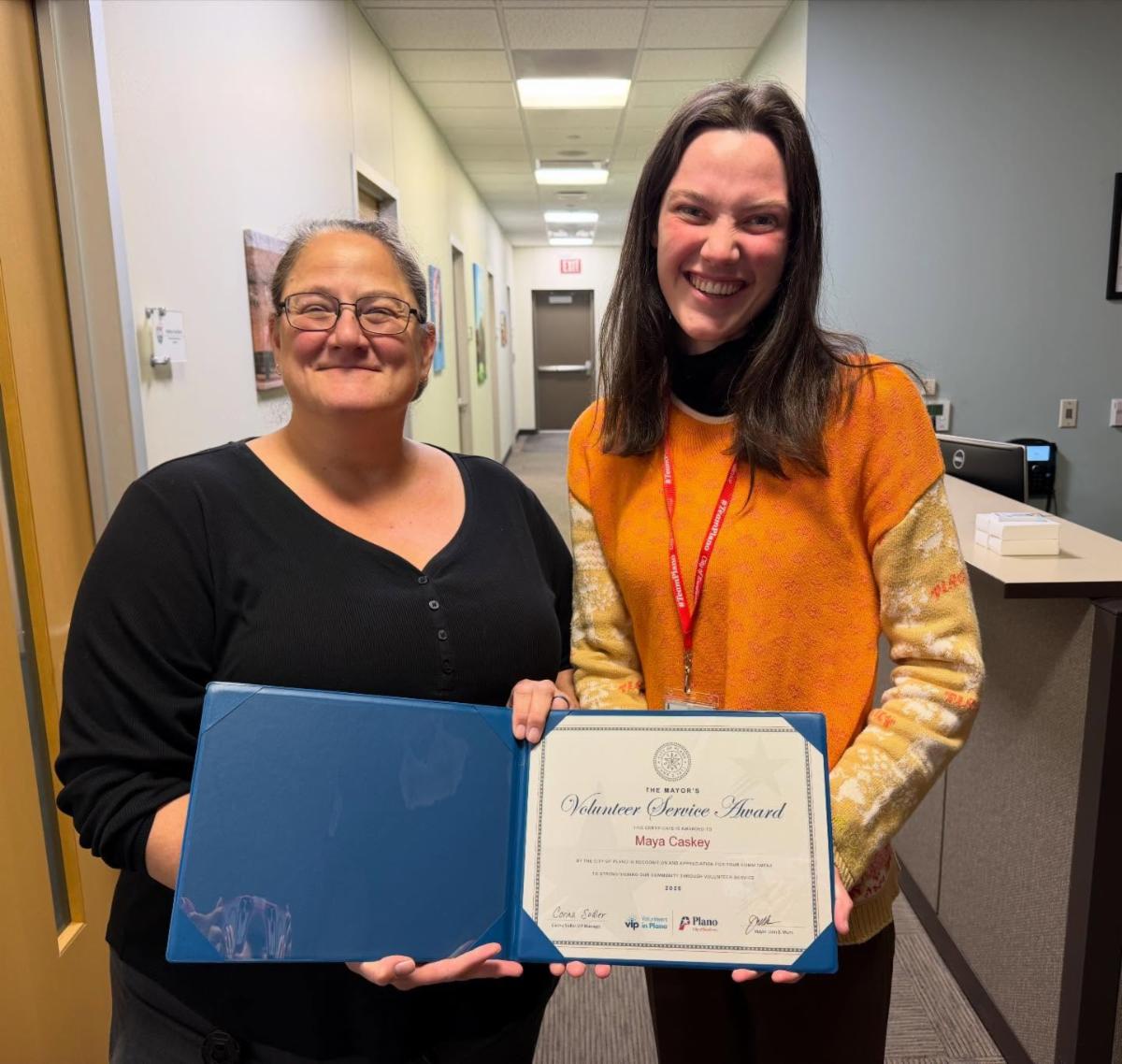Women smiling indoors holding certificate
