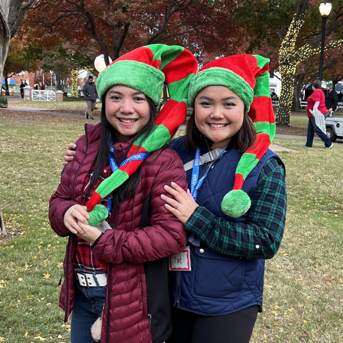 Two women smiling with red and green striped hats