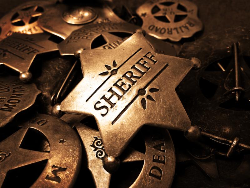 Sheriff s tin badge in pile of star law enforcement badges