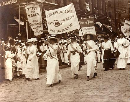 Women from the Just Government League marching and carrying suffrage banners.