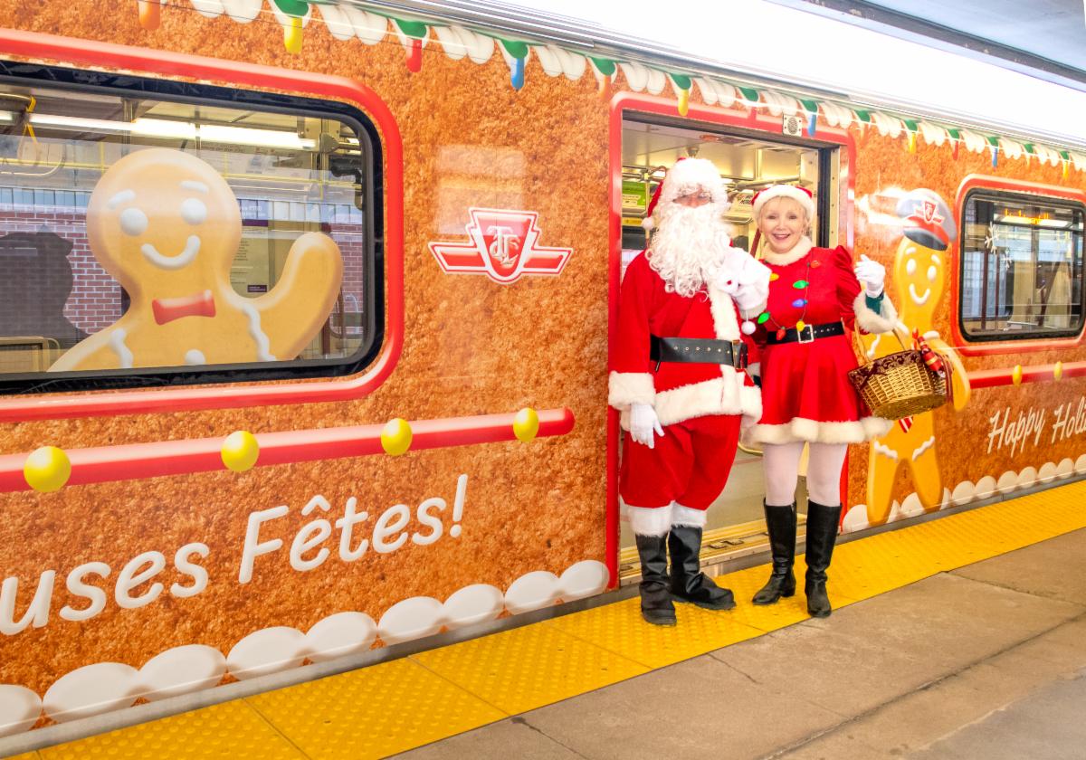 TTC subway santa and Mrs. Claus getting of a subway with the festive gingerbread train wrap