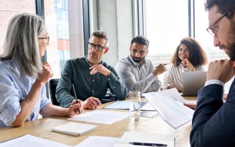 5 People seated around a board table with business papers