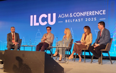 Image of 4 panelists seated on stage. ILCU AGM and Conference Belfast 2025 wording shown on backdrop of stage in white writing.