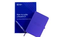 two purple handbooks and a pen. The cover of one says How to write a board CV