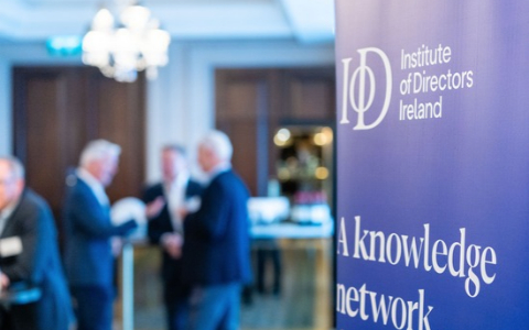 IoD banner in foreground with people blurred in the background talking