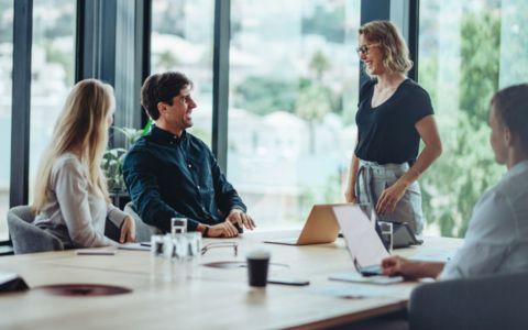 People seated and standing around a boardroom table