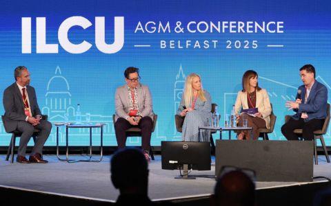 panel of five people seated on stage. ILCU AGM and conference on blue background
