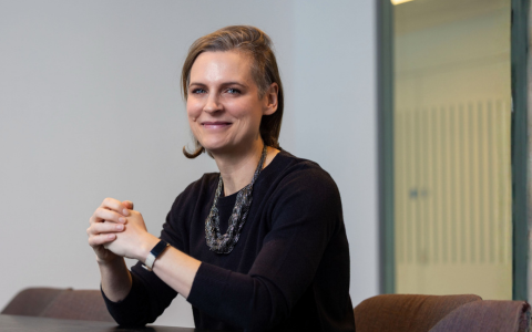 Image of person with black top. Seated at table and smiling to camera