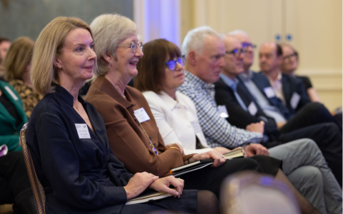 row of people seated and listening to a speaker at an event