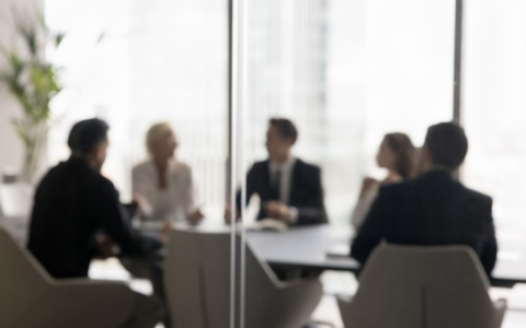 People sitting around boardroom table behind frosted glass. Abstract image